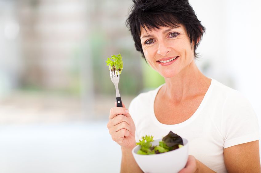 attractive mature woman with fresh green salad at home